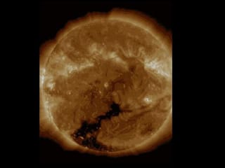 Gelb-orange Sonnenscheibe mit Gashülle darum herum. Alles scheint in Bewegung. Unten ist ein grosses, dunkles Loch zu sehen. Gelb-orange Sonnenscheibe mit Gashülle darum herum. Alles scheint in Bewegung. Unten ist ein grosses, dunkles Loch zu sehen.