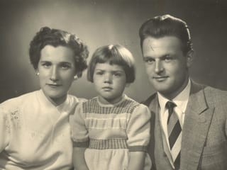 Alte Fotografie mit einem Elternpaar und ihrer kleinen Tochter in der Mitte.