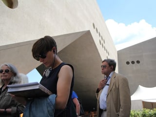 Drei Besucher stehen mit Audioguides vor der Brücke zum Altbau.