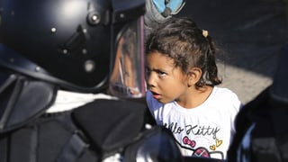 Ein Mädchen beobachtet einen mexikanischen Nationalgardisten