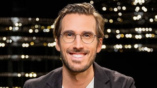 Ein Mann mit runder Brille grinst in die Kamera.