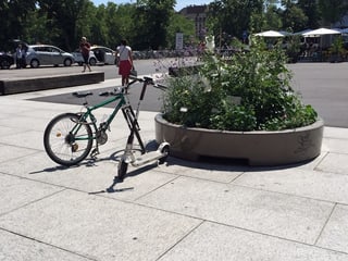 Ein E-Trottinett steht neben einem Fahrrad.