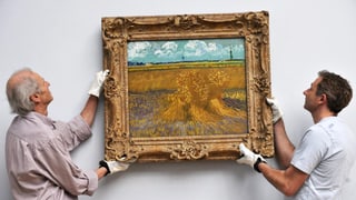 Im Museum: Zwei Männer hängen ein Bild von Vincent van Gogh an die Wand.