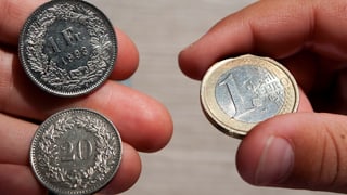 Eine Person hält in einer Hand 1.20 Fr. und in der anderen Hand einen Euro