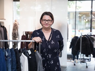Eine Frau steht vor einer Garderobenstange in einem Kleiderladen. Eine Frau steht vor einer Garderobenstange in einem Kleiderladen.
