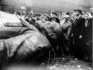 Menschen vor einer zu Fall gebrachten Stalin-Statue.