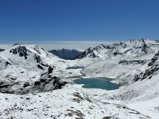 Hochalpen mit See, alles leicht verschneit, aber bei Sonnenschein