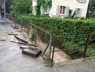 Ein Bach schiebt Holzteile auf ein Trottoir.