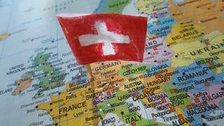 Eine kleine Schweizerfahne steckt auf einer Europakarte in Deutschland