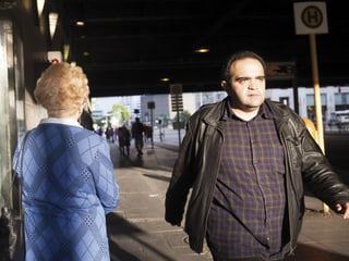Strassenszene: Ein Mann geht auf dem Bürgersteig an einer älteren Frau vorbei.