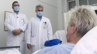 Zwei Ärzte am Spitalbett einer Patientin.