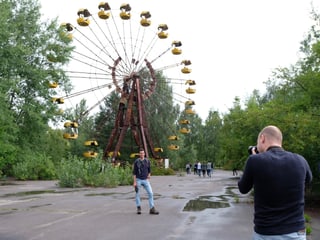 Mann macht Foto vor Riesenrad.