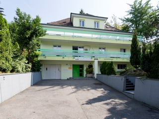 Blick auf ein grünlichen Haus mit grosser Einfahrt. Das Haus steht in einem grünen Wohnquartier. Blick auf ein grünlichen Haus mit grosser Einfahrt. Das Haus steht in einem grünen Wohnquartier.