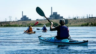 Drei Leute paddeln in Kayaks auf einem Fluss. Drei Leute paddeln in Kayaks auf einem Fluss.