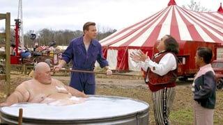 Ein dicker Mann badet. Ein Helfer (Ewan McGregor) hält eine Bürste. 