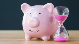 Ein Sparschwein steht neben einer Sanduhr.