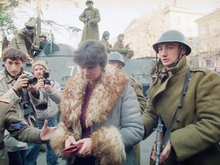 Frau, die von Soldaten abgeführt wird.