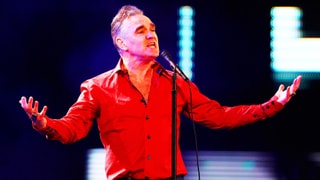 Morrissey, singend mit ausgebreiteten Armen, im knallroten Hemd