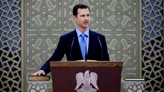 Assad an einem Rednerpult.