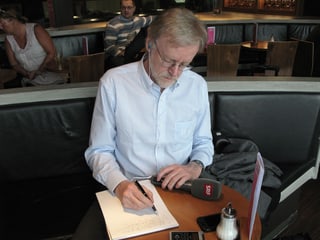 Casper Selg sitzt an einem Tisch im Flughafen-Café.