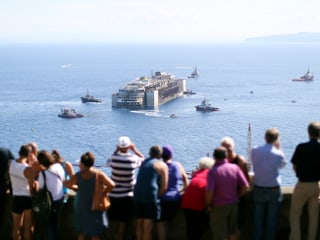 Touristen beäugen die Einfahrt der Costa Concordia.