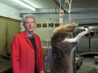 Ein Mann steht neben einem toten aufgehängten Fuchs