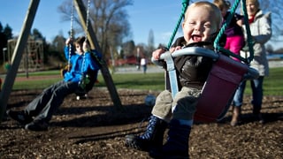 Lachende Kinder auf Schaukeln, Spielplatz