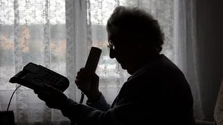 Silhouette einer älteren Frau, die den Telefonhörer abhebt