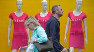 Ein Mann und eine Frau gehen an drei «Soldes»-Kleidchen tragenden Schaufensterpuppen vorbei.