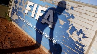 Schatten eines Fussballers auf einer Bretterwand mit Fifa-Logo