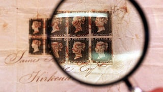 Eine Lupe zoomt auf die Briefmarken.