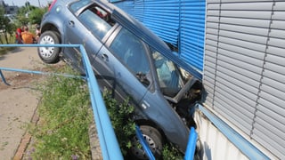 Blaues Personenfahrzeug liegt in einem Graben zwischen Trottoir und Hauswand. Der Motorenraum ist eingedrückt.