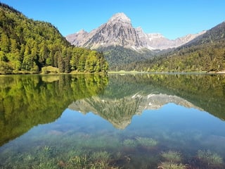 Blick auf einen Bergsee unter blauem Himmel