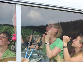 Blick ins Postauto. Menschen stehen, sitzen, lachen und klatschen.