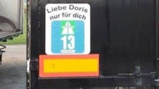 Eine grosse Autobahnvignette klebt am Heck eines Lastwagens mit der Aufschrift «Liebe Doris nur für dich».