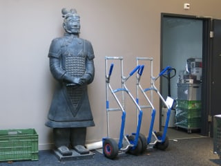 Grosse Krieger-Statue neben Lasten-Rolli