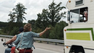 Mann und Frau auf Motorrad fahren neben Wohnmobil Mann und Frau auf Motorrad fahren neben Wohnmobil
