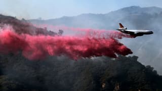 Löschflugzeuge werfen Feuer retardierendes Pulver über die Wälder ab.