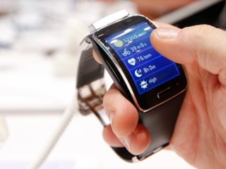 Eine Männerhand hält eine Gear S Smartwatch von Samsung. Eine Männerhand hält eine Gear S Smartwatch von Samsung.