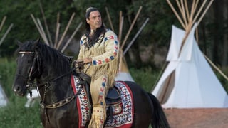 Ein als Winnetou kostümierter Mann auf einem Pferd.