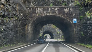 Strasse die durch einen Tunnel führt mit zwei Autos. 