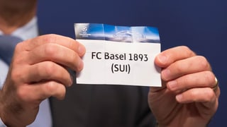 Ein Mann hält einen Zettel hoch, darauf steht Basel.