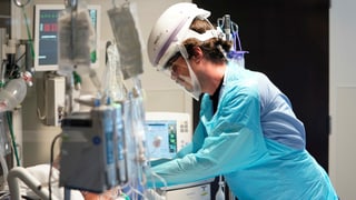 Eine Person mit Schutzausrüstung an einem Krankenbett in einem US-Spital.