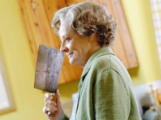 Eine alte Frau mit einem Hackebeil.