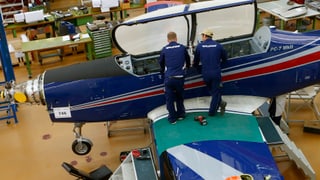 Zwei Mechaniker stehen auf dem Flügel eines Kleinflugzeuges