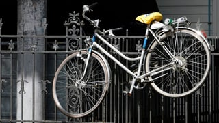 Ein Velo hängt an einem Zaun.