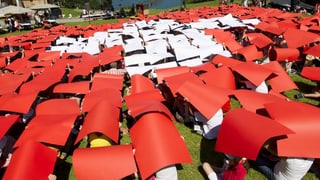 Kinder formieren sich mit farbigen Schildern zu einer grossen Schweizer Flagge.