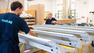 Ein Mann und eine Frau arbeiten in einer Werkhalle an speziellen Metallteilen. Ein Mann und eine Frau arbeiten in einer Werkhalle an speziellen Metallteilen.