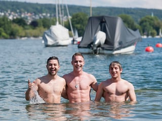 Zu sehen sind drei junge Männer, die im Zürichsee posieren.
