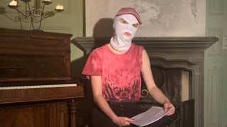 Eine Frau mit einer weissen Sturmhaube sitzt auf einem Stuhl. Auf ihrem Schoss liegt ein Stapel Papier. Eine Frau mit einer weissen Sturmhaube sitzt auf einem Stuhl. Auf ihrem Schoss liegt ein Stapel Papier.
